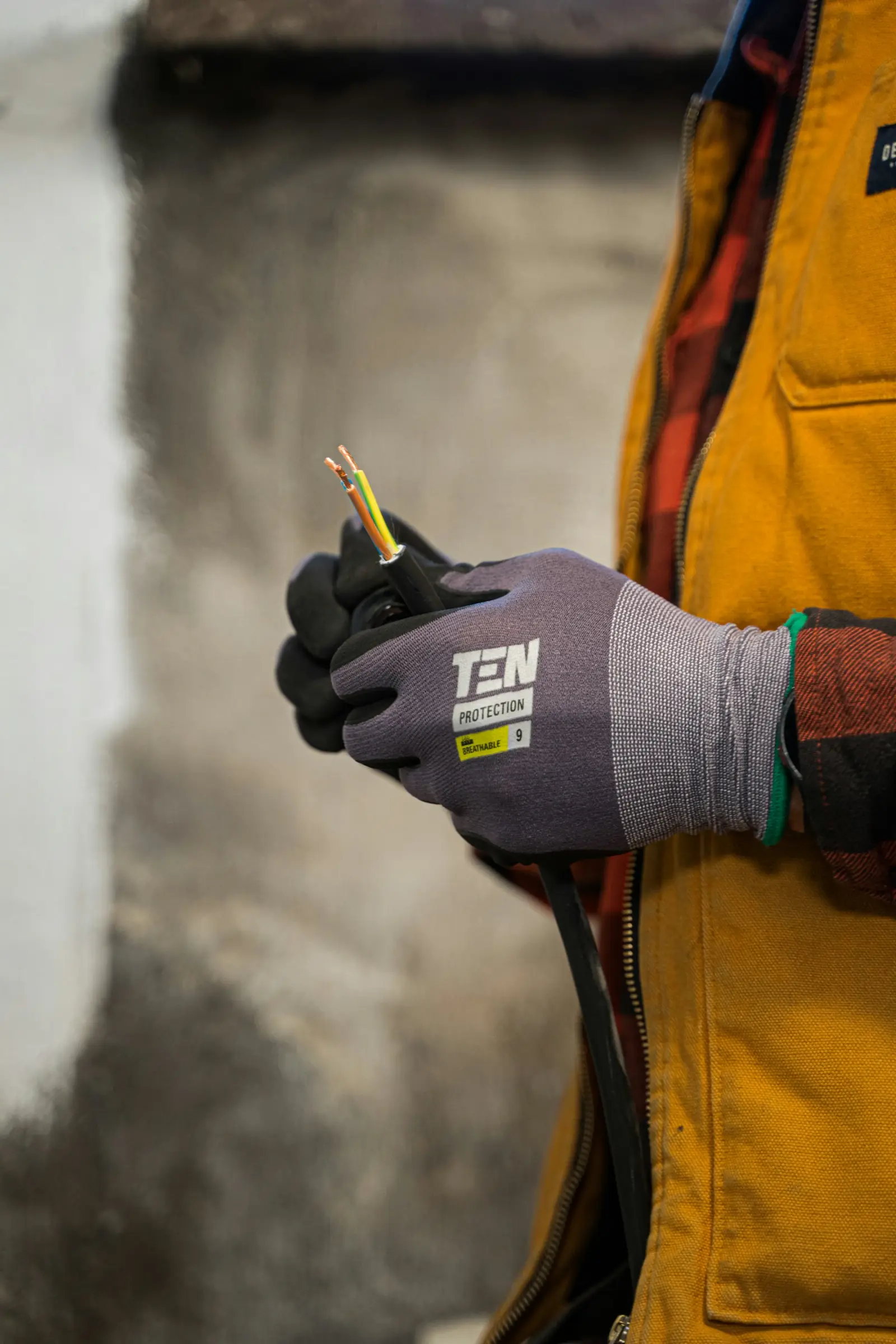 Hand im Arbeitshandschuh hält ein abisoliertes Kabel