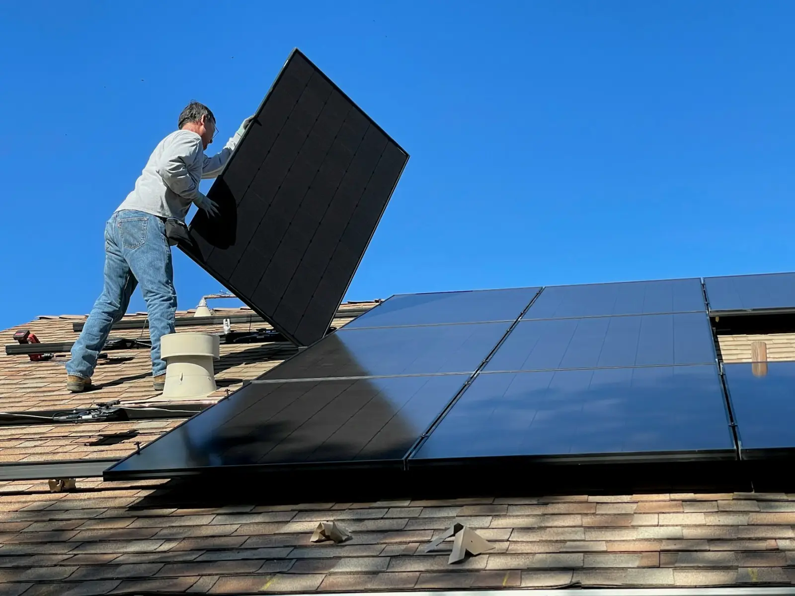 Handwerker setzt ein Solarmodul auf ein Dach