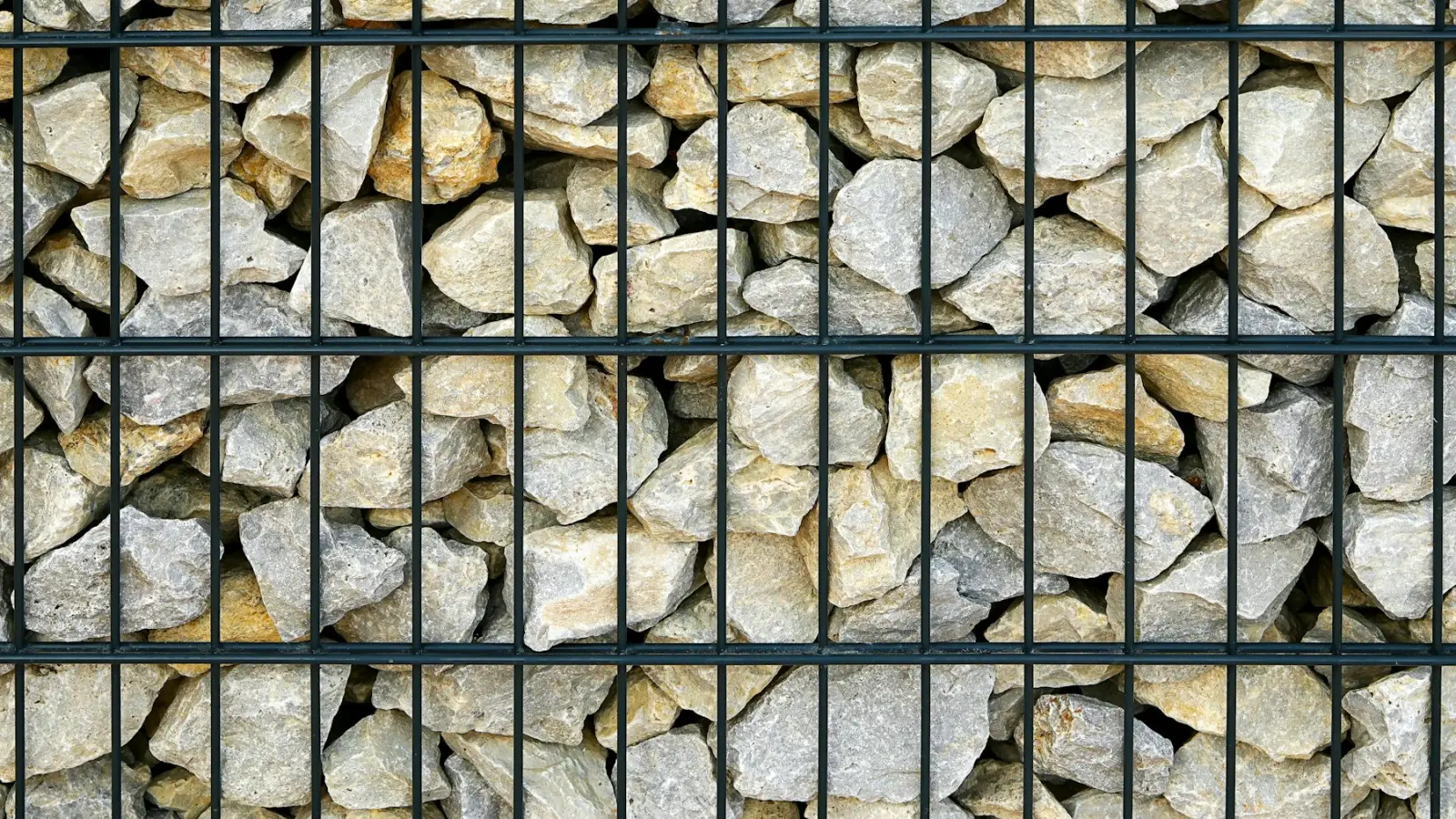 Gabionenwand mit hellem Bruchstein hinter Gitterstäben