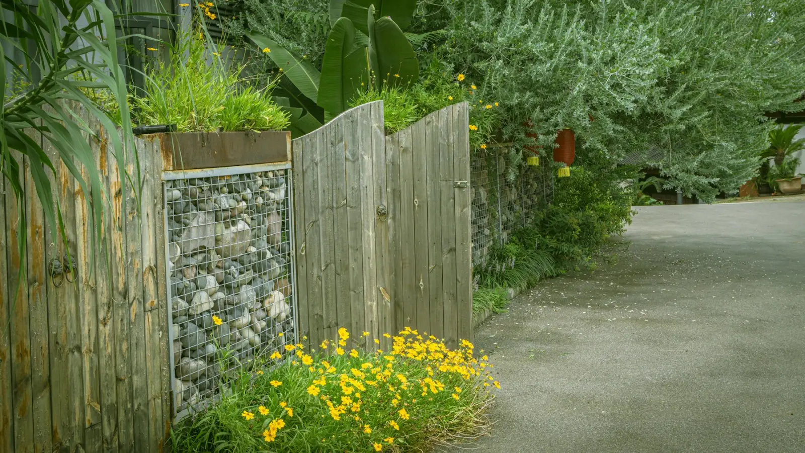 Holzzaun mit eingesetztem Gabionen-Element an einem Weg